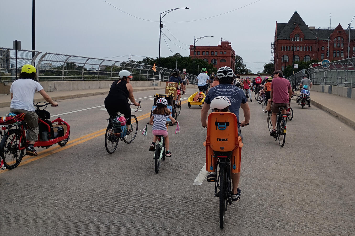 Untitled A mixed age group of bike riders shown from the rear going over the highway and train tracks on 31st St.
